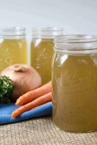 Quart sized canning jars filled with a yellow broth.