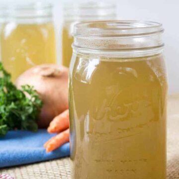 Quart sized canning jars filled with a yellow broth.