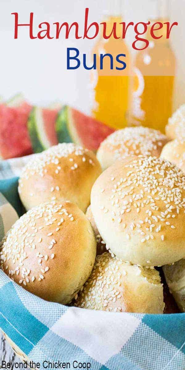 A basket full of hamburger buns with sesame seeds.