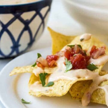 Corn tortilla chips toped with a cheese sauce and salsa.