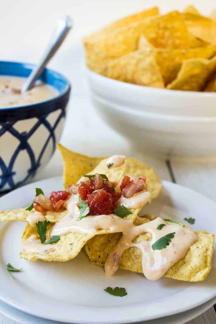 Cheese Dip poured over chips topped with a tomato salsa.