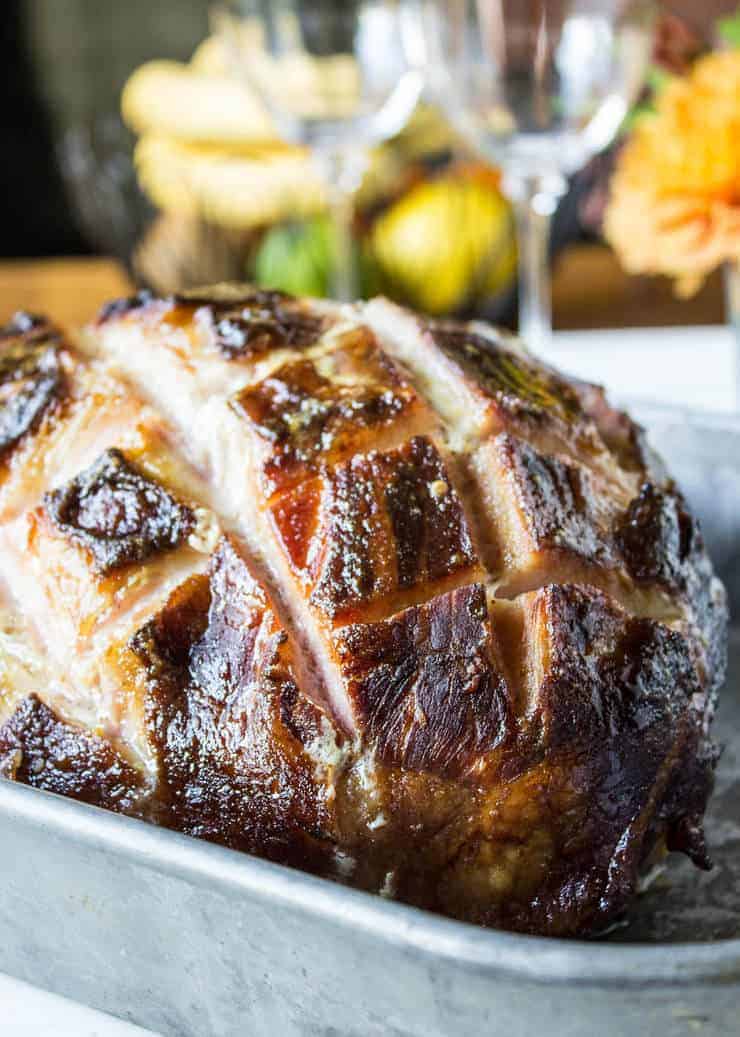 A large baked ham with slices across the top making a diagonal pattern.