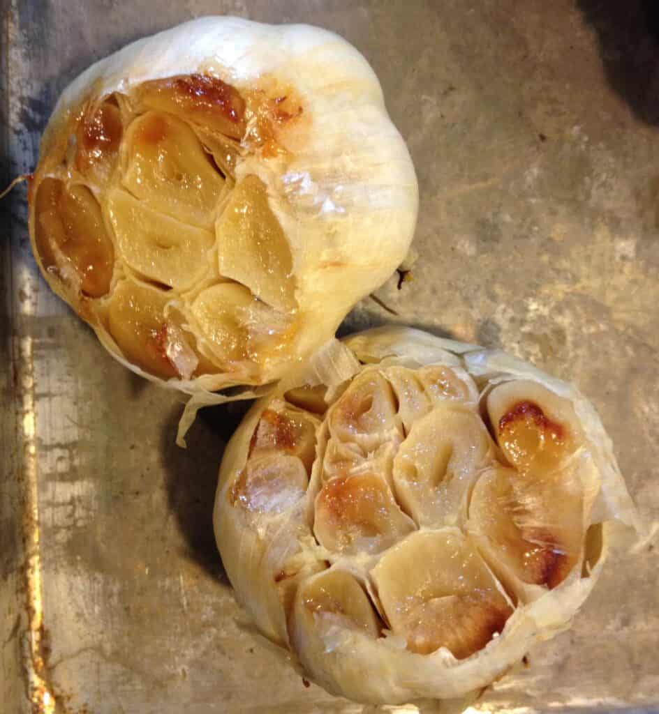 Roasted garlic halved on a baking sheet. 