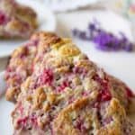 Two scones with raspberries on a small white plate.