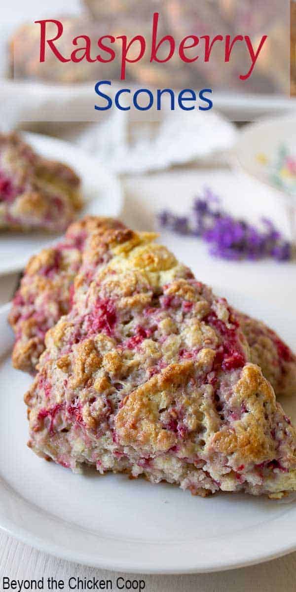 Two scones with raspberries on a small white plate.
