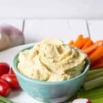 Hummus in a bowl surrounded by fresh cut veggies.