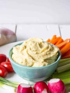 Hummus in a bowl surrounded by fresh cut veggies.