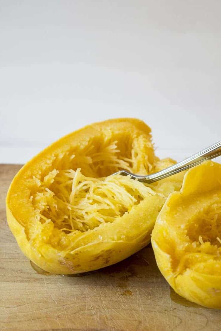 Spaghetti Squash halved with strands of squash fluffed with a fork. 