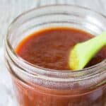 Barbecue Sauce in a glass jar with a green pastry brush.