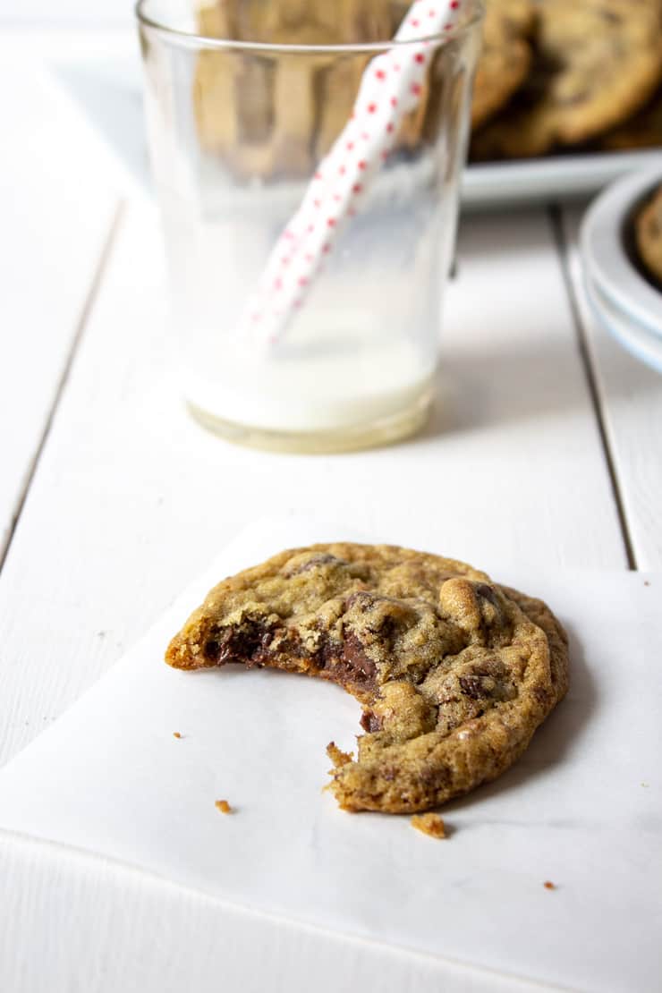 A chocolate toffee chip cookie with a bite taken out of it. 
