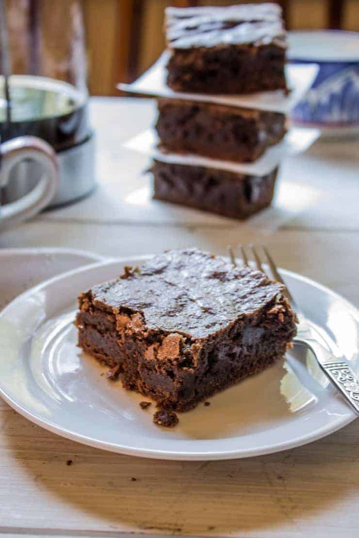 A brownie square on a white plate with a fork.