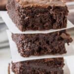 A stack of brownies with a piece of parchment paper between each brownie.