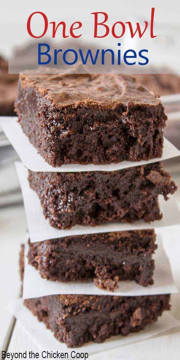 A stack of brownies with a piece of parchment paper between each brownie.