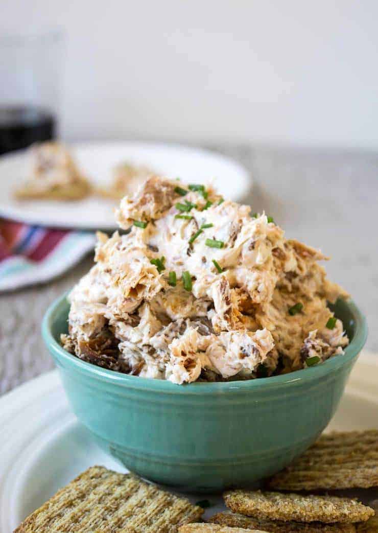 A bowl full of a dip with chunks of salmon.