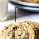 Two cookies with chocolate chips and toffee on a white board.