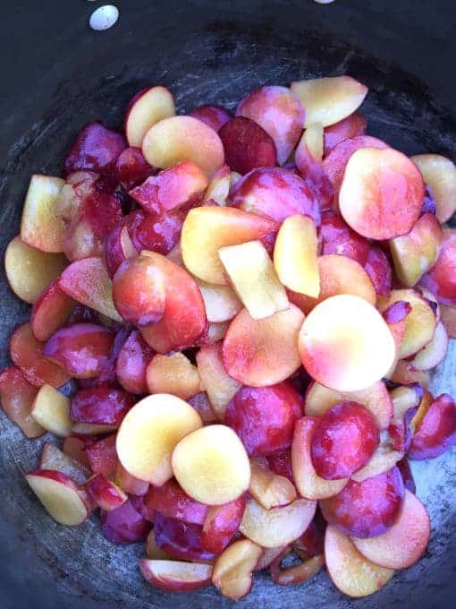 Cut up plums in a black pot.