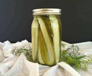 A glass canning jar filled with pickle spears.