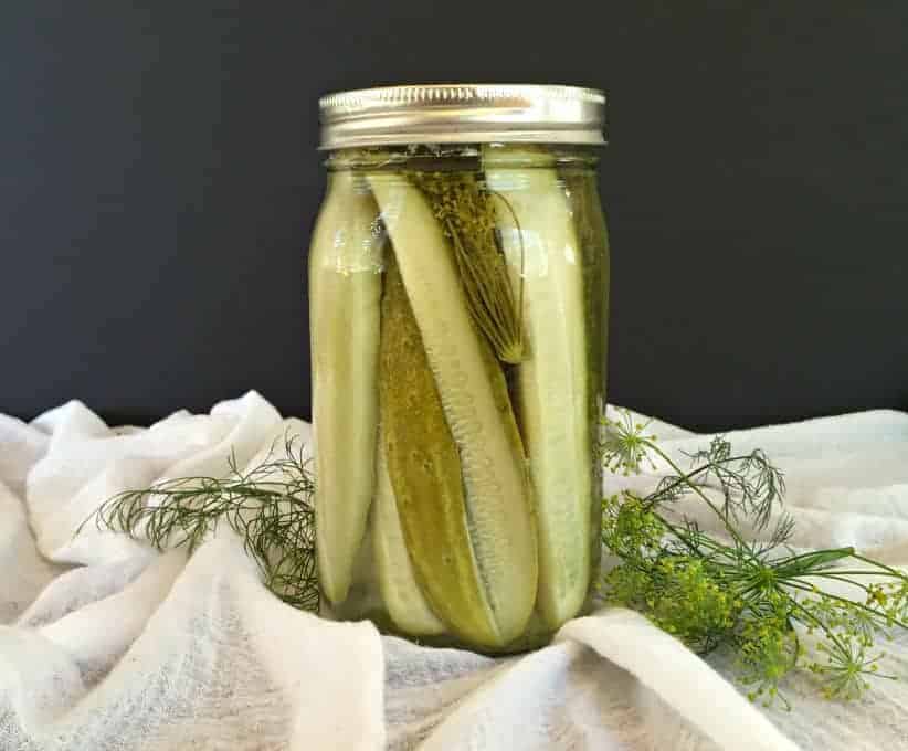A glass canning jar filled with dill pickle spears.