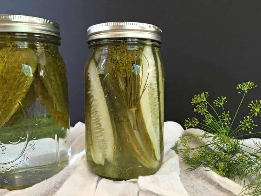 Fresh dill seed next to a jar of dill pickles.