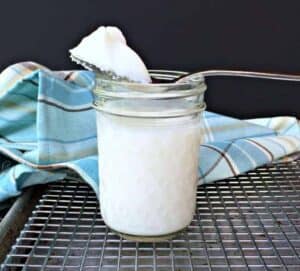 A spoonful of lard on top of a glass jar.