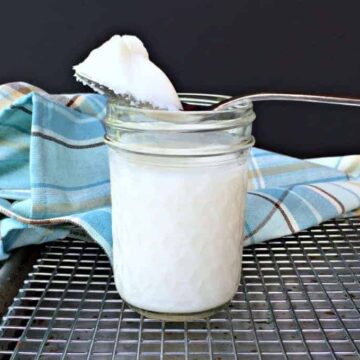 A spoonful of lard on top of a glass jar.