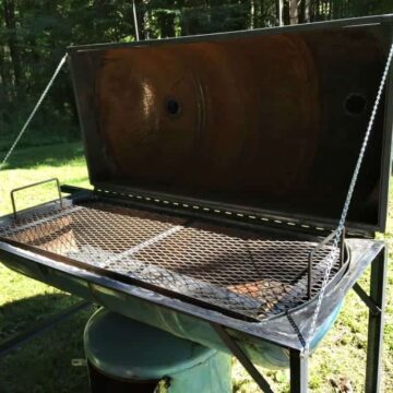 A large smoker and grill with the lid opened.