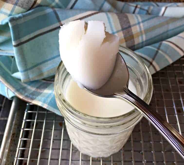 A spoonful of lard over a glass jar.