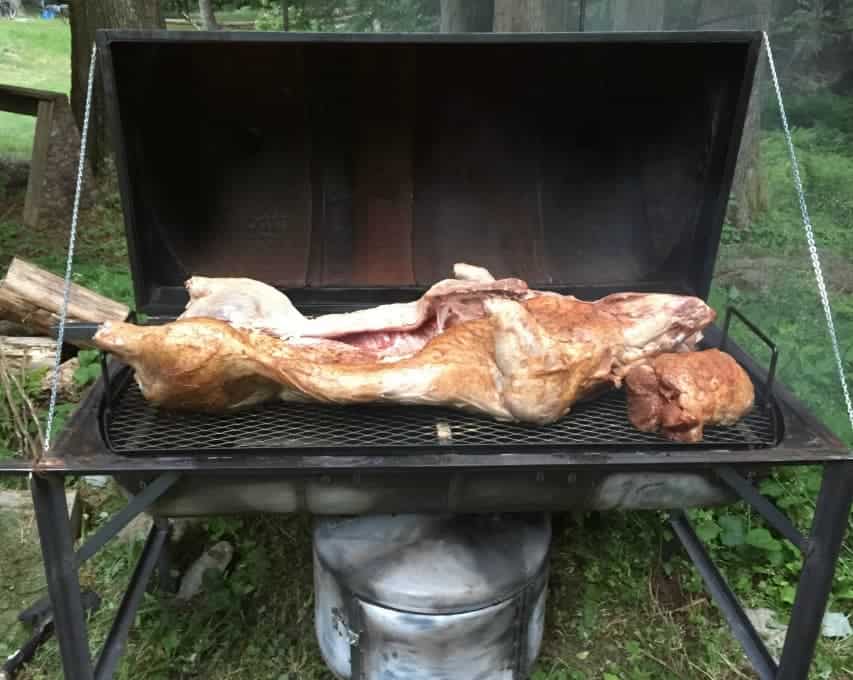 A whole pig laying on top of a bbq grill.