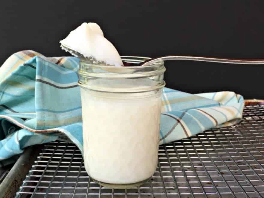 Lard on a spoon sitting on top of a jar of lard.