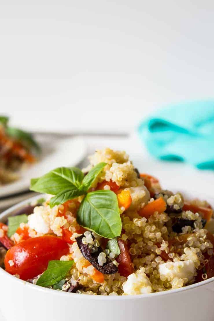 A salad with quinoa, fresh tomatoes, olives and fresh basil.