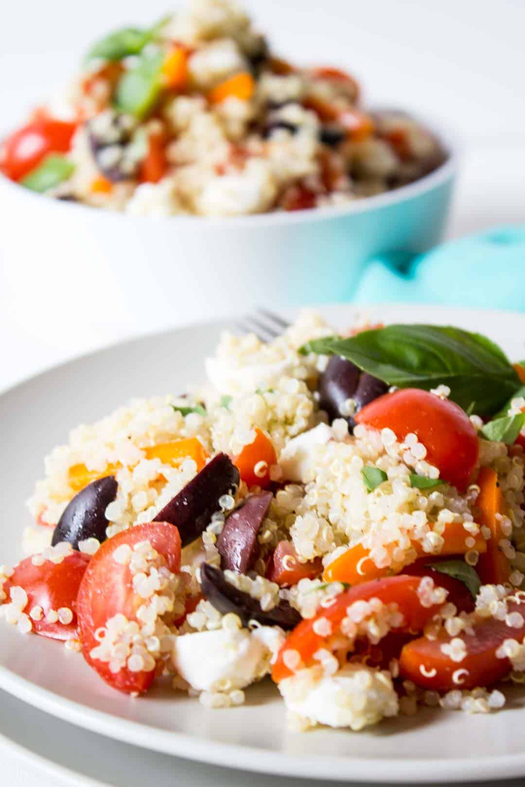 White plate filled with quinoa and fresh veggies.