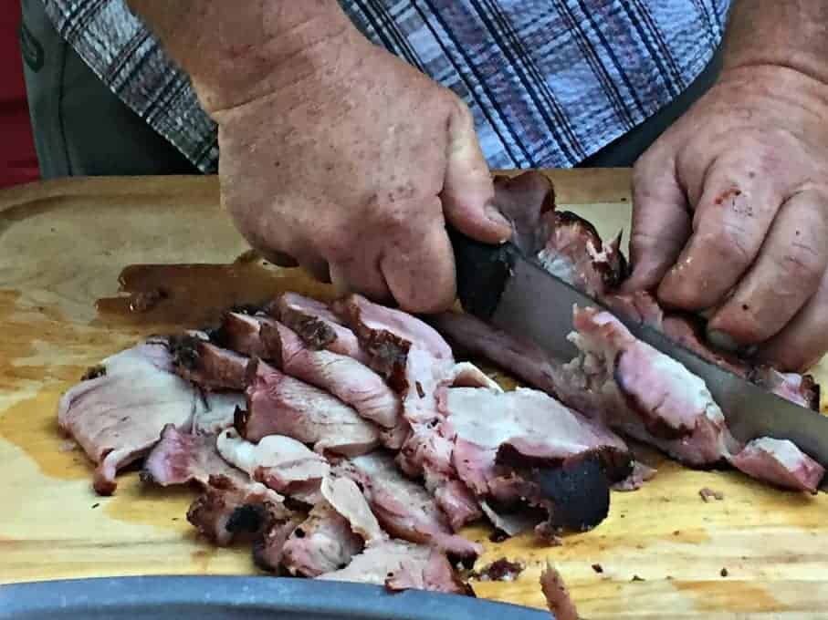 Smoked Pork being sliced on a wooden cutting board.