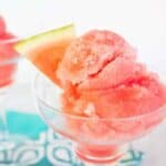 Scoops of a pink sorbet in a glass serving dish.