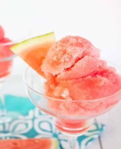 Scoops of a pink sorbet in a glass serving dish.