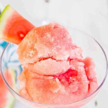 Scoops of pink colored sorbet in a glass serving dish.