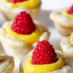 Mini tarts filled with lemon curd and topped with a fresh raspberry.