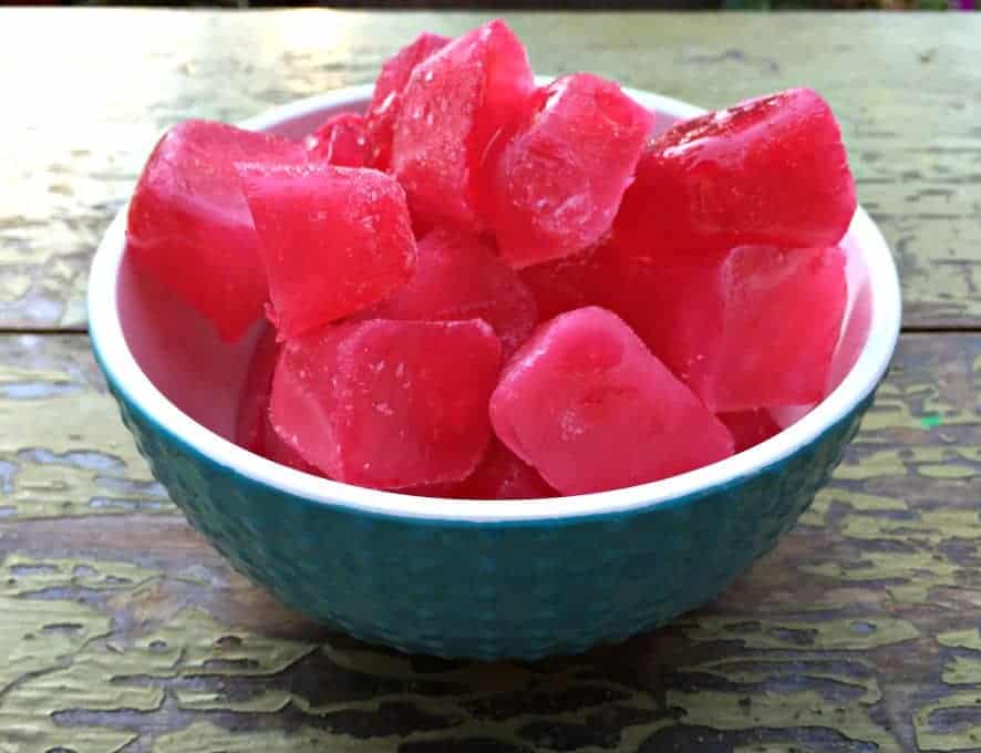 Plum juice ice cubes in a turquoise and white bowl.