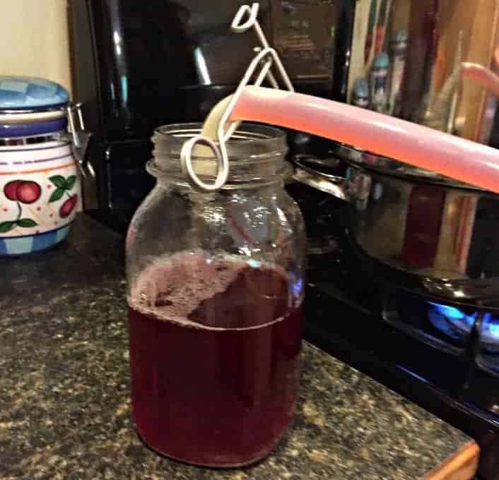 Adding juice into a glass quart jar.