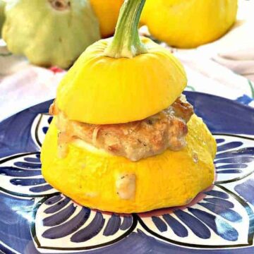 Stuffed yellow squash with a top sitting on a blue patterned plate.