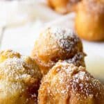 Three small round apple fritters on a white plate.