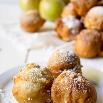 Three apple fritters on a white plate.