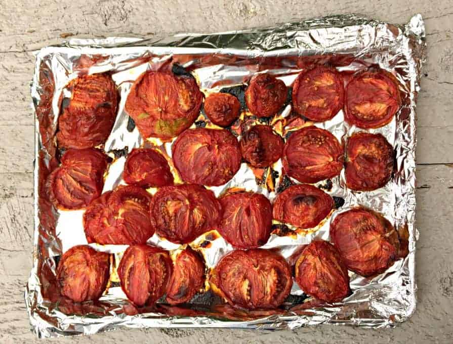 Oven roasted tomatoes on a foil lined baking sheet.