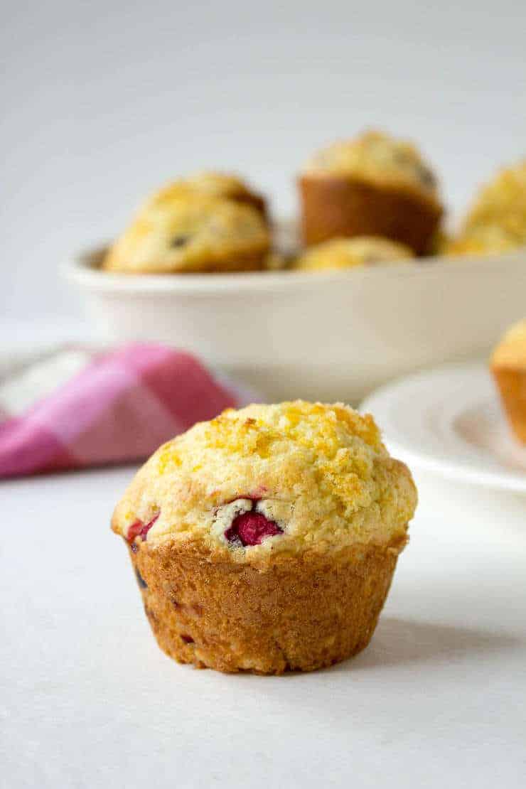 A muffin with cranberries and orange zest on the top. 