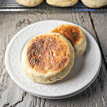 Two browned english muffins on a plate.