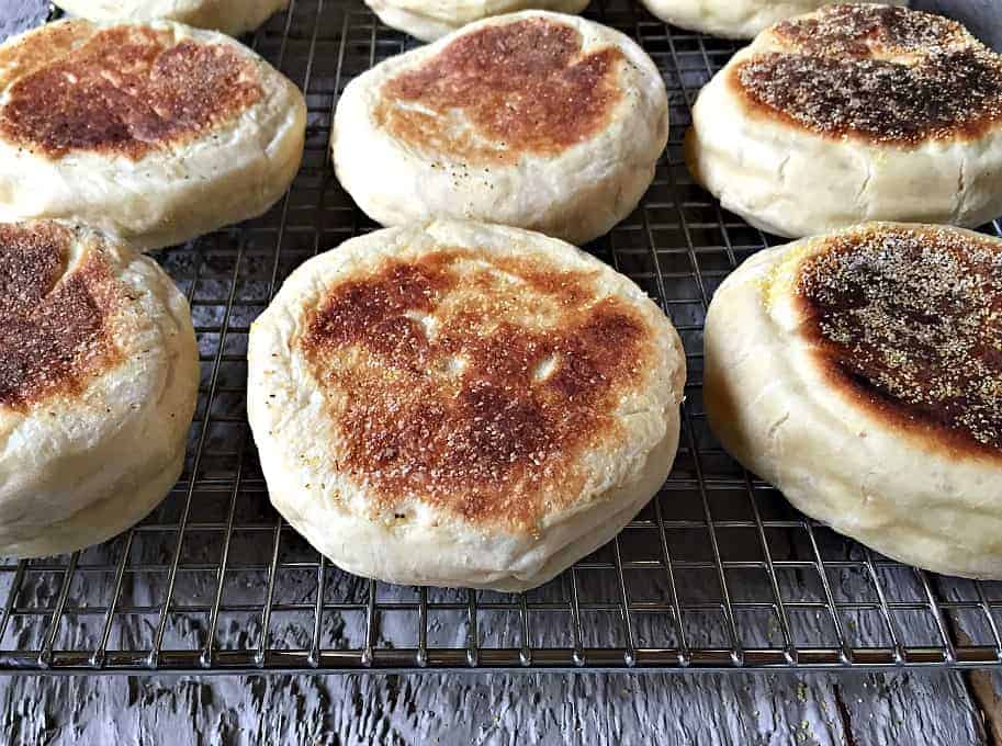 Homemade English Muffins cooling on a baking rack.