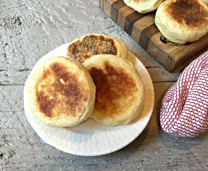 Three English muffins on a white plate.