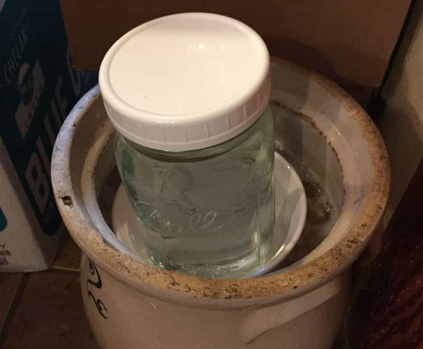 Weighting down the sauerkraut with a quart glass jar filled with water.