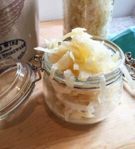 A glass crock overfilling with sauerkraut.