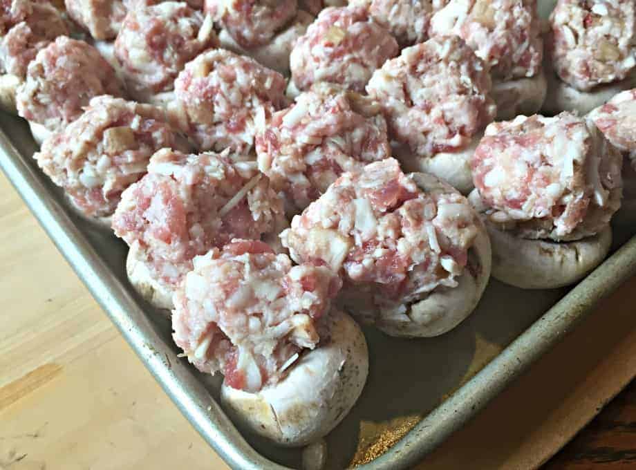 Mushrooms filled with sausage and cheese on a baking sheet.