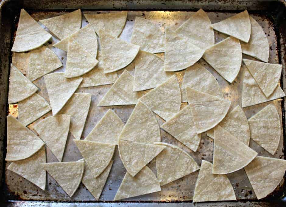 Corn tortillas cut into wedges on a baking sheet.